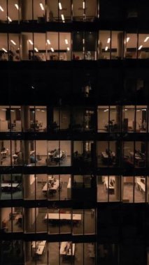 Ofis binasının göz kamaştırıcı hava manzarası. Işıklandırılmış boş ofisler. Geceleri yakın plan parlıyor..