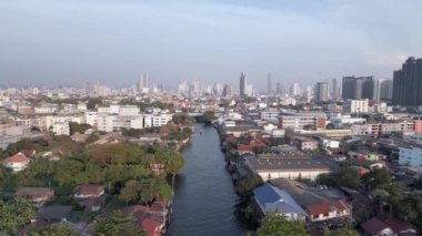 Bangkok şehrinin göz kamaştırıcı gökdelenleriyle gökdelenler yükseliyor ve Chao Phraya Nehir Kanalı 'nda bir tekne su yolunda ilerliyor..