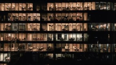 Ofis binasının göz kamaştırıcı hava manzarası. Işıklandırılmış boş ofisler. Geceleri yakın plan parlıyor..