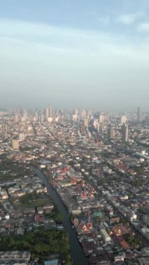 Uzaktaki gökdelenlerle Bangkok şehrinin göz kamaştırıcı hava manzarası ve günbatımından hemen önce Chao Phraya Nehri kanalı..