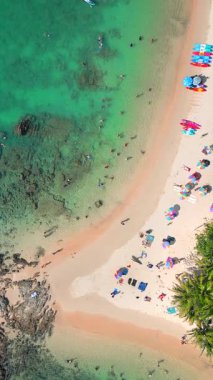 Phuket Adası 'nın canlı kıyı şeridi renkli şemsiyeler ve tropikal bir plajda dinlenen insanlar.. 