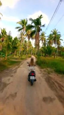 Tropik bir adada scooter süren bir kadın. Özgürlük kavramı.