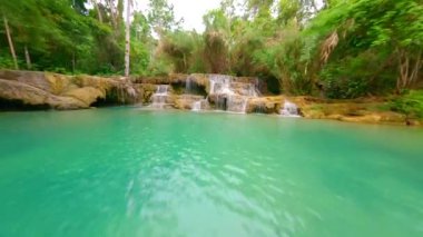 FPV insansız hava aracı Laos 'taki ormanda suya yakın bir nehir üzerinde uçuyor..