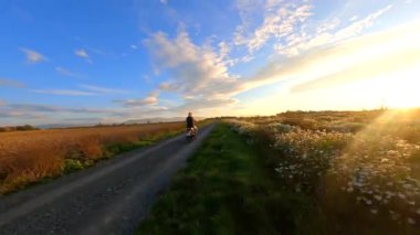 Sonbaharda kırsal yolda motosiklet süren bir kadın onu FPV drone takip ediyor..