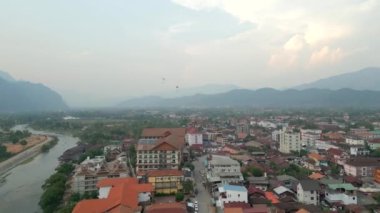 Şehrin üzerinde uçan yamaç paraşütçüleriyle Vang Vieng 'in güzel hava manzarası.