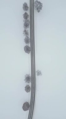 Karlı kışta araba süren bir kır yolunun en üst görüntüsü.