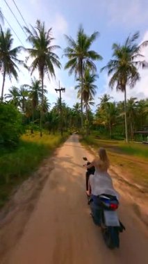 Tropik bir adada scooter süren bir kadının hava görüntüsü..