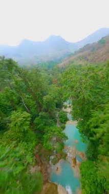 Laos 'taki tropik Kuang Si Şelalesi üzerinde dinamik FPV insansız hava aracı uçuşu.