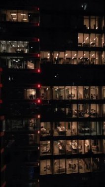 Geceleri ışıl ışıl parlayan boş ofisleri olan bir ofis binasına yakın çekim..