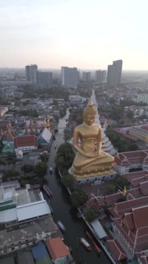 Gün batımında Bangkok 'taki dev altın Buda' nın muhteşem hava manzarası. Arka planda güzel bir şehir silüeti var..