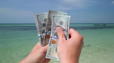 Tropikal plajda Amerikan dolarlarını sayan eller. Kapat..