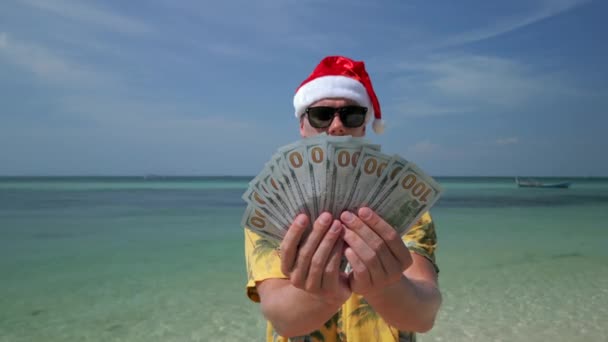 在热带海滩上戴圣诞礼帽的男人数着美元 — 图库视频影像