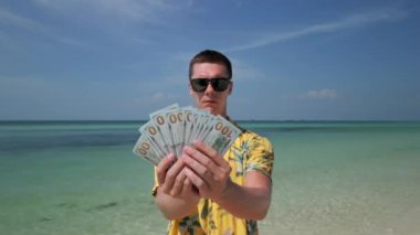 Tropikal plajda Amerikan doları tutan adam..