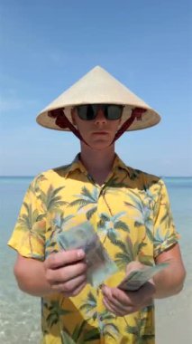 Vietnam şapkalı adam Vietnam 'da tropik plajda Vietnam Dong' unu sayıyor. Kapat..