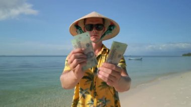 Vietnam şapkalı adam Vietnam 'da tropik plajda Vietnam Dong' unu sayıyor. Kapat..