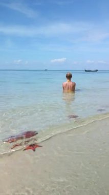 Beyaz kadın Vietnam 'daki Phu Quoc Adası' nda tropikal denizde deniz yıldızıyla dinleniyor.