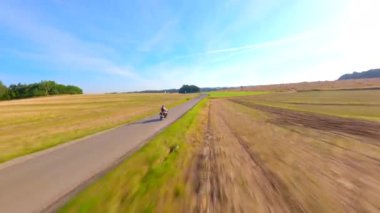 FPV insansız hava aracı yazın tarlalardan geçen eski bir motosikleti takip ediyor.