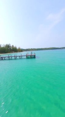 Turkuaz deniz kenarında yoga yapan beyaz bir kadın.