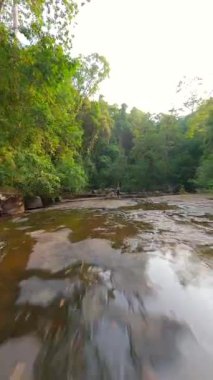 Kafkasyalı kadının FPV 'si Tayland' daki tropikal yağmur ormanlarında nehir kenarında yoga yapıyor.