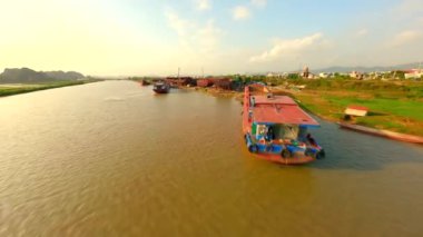 FPV, Ninh Binh, Vietnam 'da nehir kanalı boyunca büyük mavnalar inşa eden bir sanayi tersanesi üzerinde uçuyor.