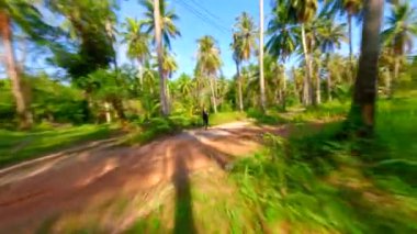 Beyaz kadın Tayland 'da tropik adalarda palmiye ağaçları olan manzaralı bir yolda koşuyor..