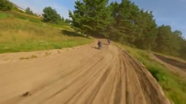 FPV insansız hava aracı bir motokros pistinde yarışçıları kovalıyor. Yüksek hız