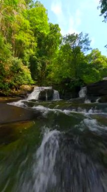 Tayland 'daki tropikal bir yağmur ormanında çağlayan nehrin üzerinden yumuşak bir FPV uçuşu
