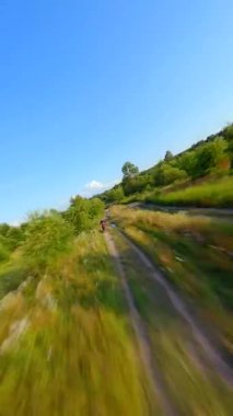 FPV İHA 'sı yüksek hızda motokros yarışçısını kovalıyor. Ekstrem sporlar, dayanıklılık, adrenalin kavramları.