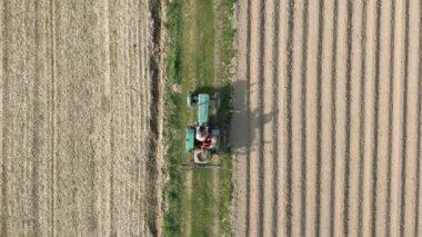 Bir traktörle tarladan geçen çiftçilerin hava görüntüsü.