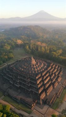 Endonezya Yogyakarta 'da güneş doğarken görkemli Borobudur Tapınağı ve Merapi yanardağının hava manzarası.