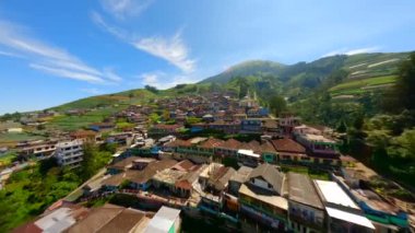 Sumbing volkanı, Central Java, Endonezya yamaçlarındaki pitoresk köy üzerinde sinematik FPV uçuşu