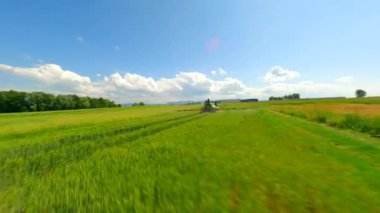 Tarım alanı püskürten bir traktörün arkasındaki yumuşak FPV uçuşu