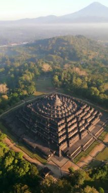 Endonezya Yogyakarta 'da güneş doğarken görkemli Borobudur Tapınağı ve Merapi yanardağının hava manzarası.