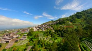 Sumbing volkanı, Central Java, Endonezya yamaçlarındaki pitoresk köy üzerinde sinematik FPV uçuşu