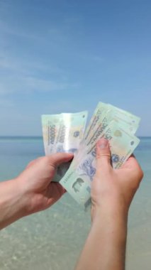 Vietnam 'da tropikal plajda Vietnamlı Dong' u sayan eller. Kapat..