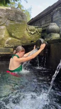 Kafkasyalı kadın, Endonezya, Bali 'deki Pura Tirta Boş Tapınağı' ndaki arındırma ayininde kafasını kutsal suya daldırıyor.