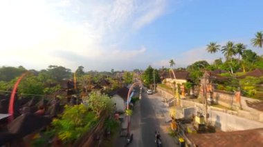 Ubud, Bali, Endonezya 'da düzenlenen Galungan tatili sırasında geleneksel köy üzerindeki sinematik FPV uçuşu.