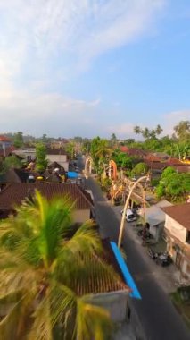 Ubud, Bali, Endonezya 'da düzenlenen Galungan tatili sırasında geleneksel köy üzerindeki sinematik FPV uçuşu.