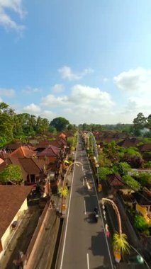 Ubud, Bali, Endonezya 'da düzenlenen Galungan tatili sırasında geleneksel köy üzerindeki sinematik FPV uçuşu.