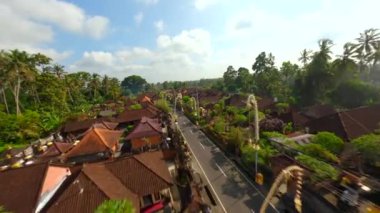 Ubud, Bali, Endonezya 'da düzenlenen Galungan tatili sırasında geleneksel köy üzerindeki sinematik FPV uçuşu.