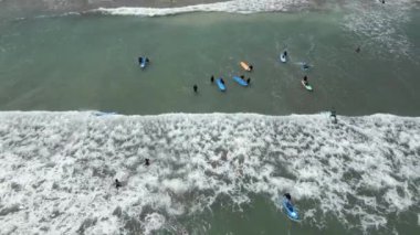 Okyanusta, Bali 'de, Endonezya' da sörf dersleri alan insanların havadan görünüşü