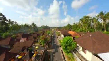 Ubud, Bali, Endonezya 'da düzenlenen Galungan tatili sırasında geleneksel köy üzerindeki sinematik FPV uçuşu.