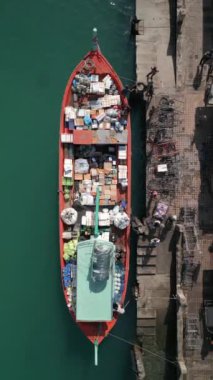 Tayland 'daki adanın iskelesinde yiyecek ve erzak dolu bir teknenin havadan görüntüsü.