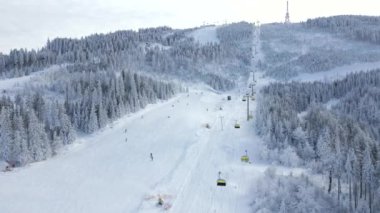 Kar yamacındaki kayakçıların ve snowboardcuların hava manzarası.