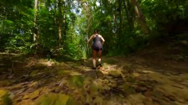 Tayland 'da tropikal yağmur ormanlarında ağır çekimde koşan beyaz atletik kadın.