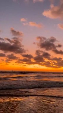 Güzel günbatımı renkleri, Bali 'de gökyüzünü ve okyanus dalgalarını kaplıyor.