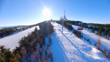 Güneşli bir günde kayakçılar ve snowboardcularla kayak pistinde yumuşak bir FPV uçuşu.