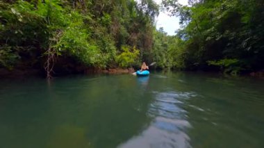 Tayland 'da tropikal bir yağmur ormanında kano süren bir kadın.