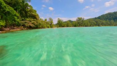 Tayland 'da tropik bir adada kristal berrak denizde kürek çeken bir kadının FPV görüntüsü.