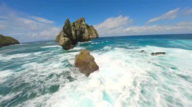 Endonezya, Bali 'deki Nusa Penida Adası' ndaki Atuh Sahili 'ndeki turkuaz okyanus suları üzerinde sinematik FPV uçuşu